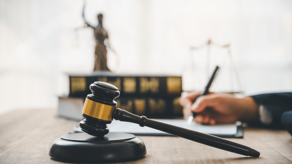 A lawyer holding a book and pen on a desk with a gavel