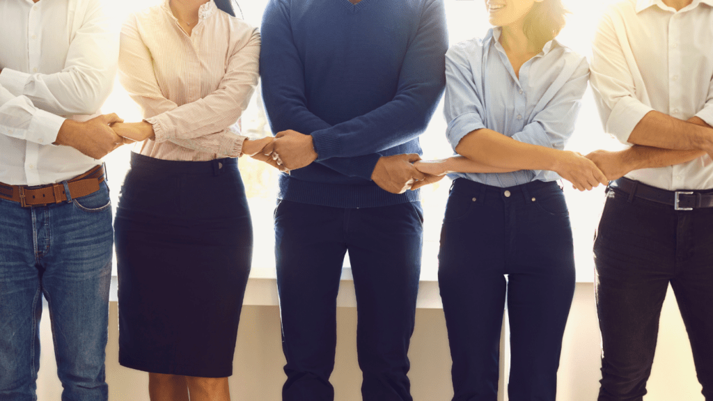 Office employees standing in a row holding hands