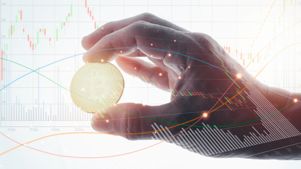 a hand holding a gold coin in front of a stock market graph