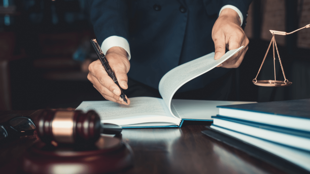 A lawyer holding a book and pen on a desk with a gavel