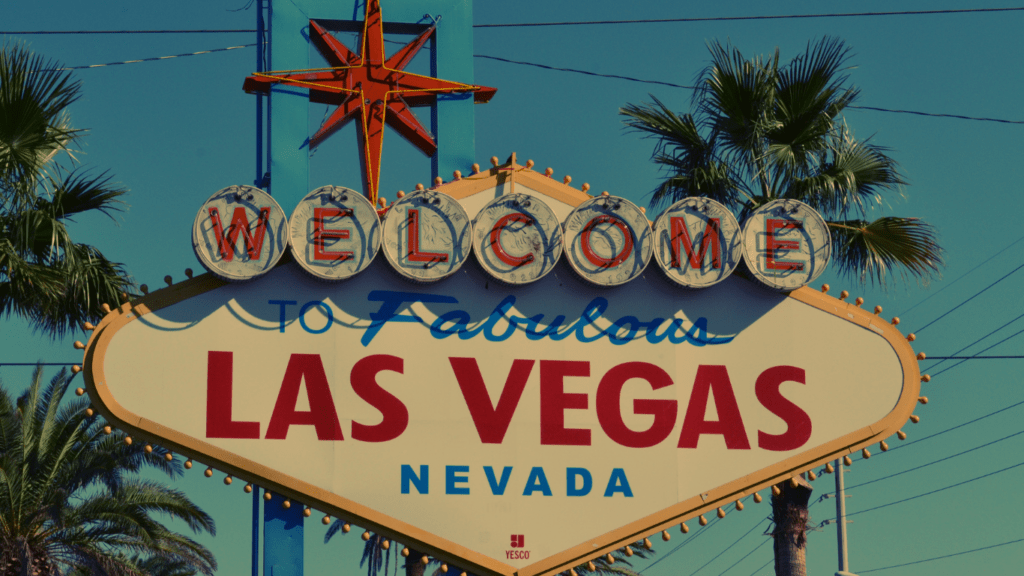 a welcome sign for Las Vegas in front of palm trees