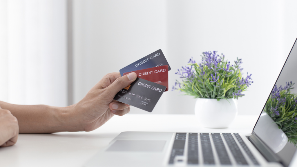 a person holding a credit card in front of a laptop