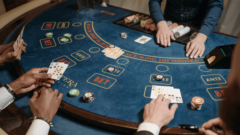 a person holding a pair of playing cards in front of a casino table