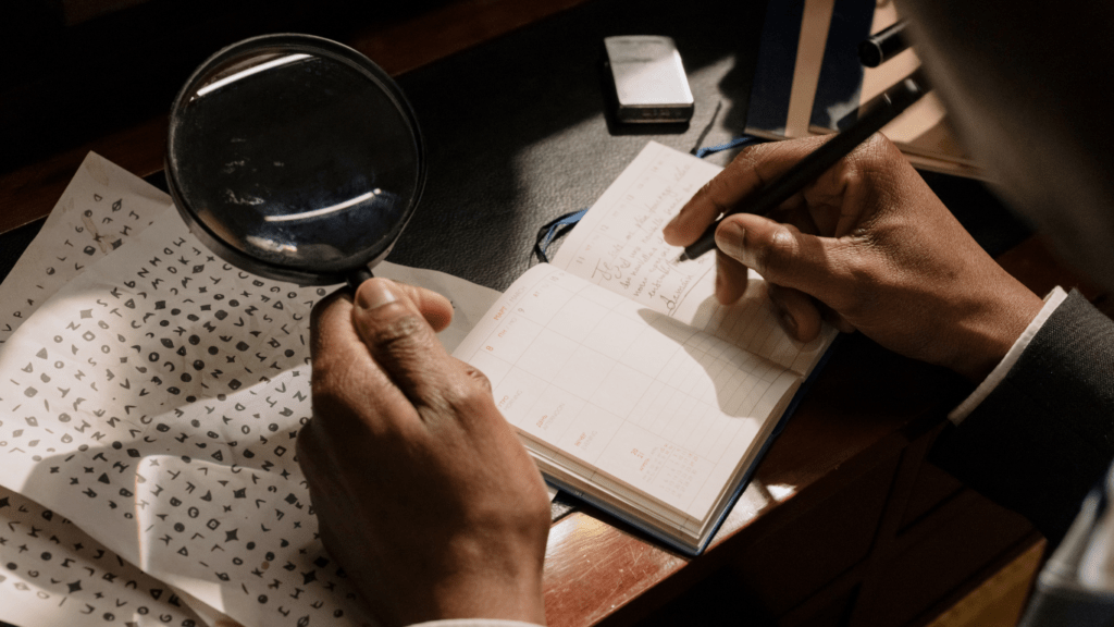 a person in a suit holding a magnifying glass over a piece of paper