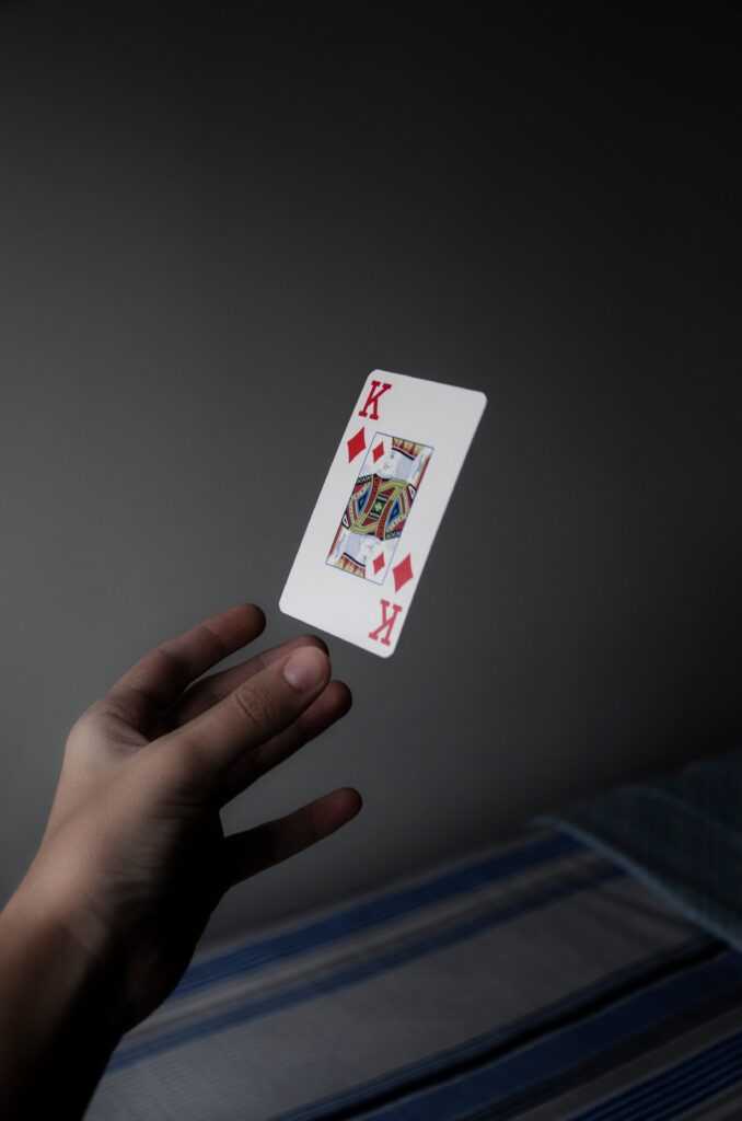 A hand elegantly holds a floating King of Diamonds card against a subdued background.